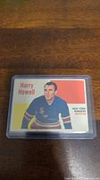 Photo of the 1960-61 Topps Harry Howell hockey card in its protective card sleeve, showing the front design of the card with player image and text.