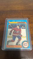Photo of 1979-80 OPC Larry Robinson hockey card with Montreal Canadiens in protective plastic sleeve on wood surface.