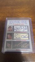 Front view image of the Iconic Ink Triple Cuts facsimile autograph card featuring images and printed signatures of Wayne Gretzky, Gordie Howe, and Mario Lemieux in separate sections, encased in clear protective plastic.