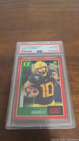 Front view of the 2020 Panini Score Justin Herbert rookie card graded PSA 8 in PSA holder.
