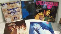 Five vinyl records displayed showing front cover artwork. Shows named artists and genres with visible wear on some covers.