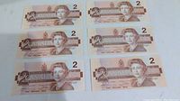 Six 1986 Canadian $2 bills laid out in two rows of three, showing the front side with Queen Elizabeth II portrait.