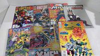 Photo showing 7 various X-Men Marvel comic books arranged overlapping on flat surface.