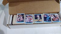 Open box showing neatly arranged baseball cards in multiple rows with visible card faces showing players in action.