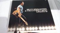 Front cover of the box set showing Bruce Springsteen playing guitar with stage lights below, text 'Bruce Springsteen & The E Street Band Live 1975-85'