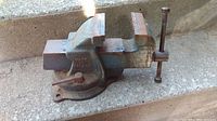 Side view of heavy metal vise showing rust, wear, embossed 'Made in Canada' mark.