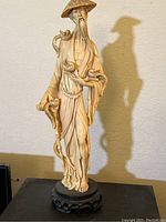 Full view of the 20-inch tall Asian man figurine wearing a conical hat, standing on black decorative base