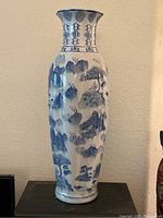 Full height view of the tall blue and white vase showing mountain and tree landscape motif.