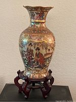 Full view of the ornate hand-painted vase on the wood stand showing height and shape.