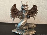 Front and angled side view showing detailed wing feathers, dragon face with horns, beard, and claws.