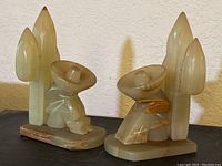 Pair of carved stone figures and cactus plants on black surface against wall