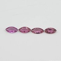 Four marquise pink tourmaline gemstones arranged in a line on a white background showing their color and shape.