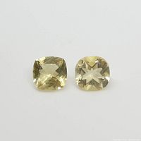 Top view of two yellow square cushion cut heliodor gemstones showing their facets and color.