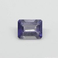 Close-up image of rectangular violet-blue iolite gemstone showing cut and color