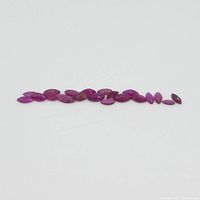 Twenty marquise-cut pink-red rubies laid out in a row on a white background, showing a gradual size range and uniform color.