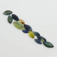 Photo of 12 marquise-shaped sapphires in various sizes and colors including blue, green, yellow, and orange on a white background.
