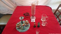 Full view of all items on table including condiment set, lamp, A&W mugs, and figurines