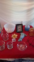 Full view of the clock and various glassware and decorative items on a red cloth background.