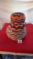 Stack of three knitted cushions showing overall size and colorful zigzag pattern.