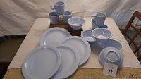 Photo of full set of Melmac dishes including plates, mugs, bowls and saucers on table.