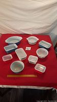 Full set of Pyrex bowls and storage containers arranged on red cloth background with measuring ruler