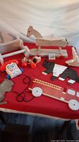 Wide shot of the lot showing wooden rocking horse, pull toys, and wooden decor items on a red surface with white backdrop.