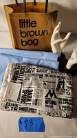 Lot contents showing the Little Brown Bag, Harry Potter fabric with newspaper print design, blue broadcloth fabric, and two white plastic hand molds.