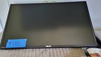 Front view of ASUS monitor screen with black bezel and ASUS logo, placed on a beige fabric surface.