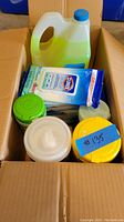 Box containing multiple cleaning wipe containers and a large jug of Mr. Clean