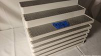 Photo showing six stacked stepped storage shelves with grey dotted non-slip surfaces on each step.