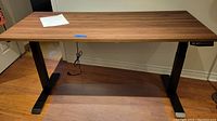 Full view of desk showing walnut-finish tabletop and black metal base.