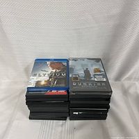 Two stacks of DVDs with 'Elysium' and 'Dunkirk' on top, showing assortment and quantity.