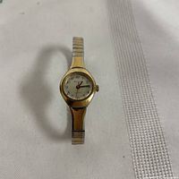Front view of vintage ladies Armitron wristwatch showing white dial with black numerals and red second hand, gold-tone bezel and silver-tone band.