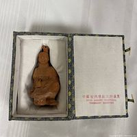 Figure seated inside decorative lined box, showing overall lot contents