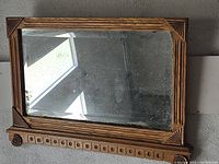 Full view of antique oak framed mirror showing overall condition, frame detail, and reflective surface wear.