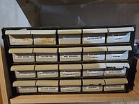 Front view of labeled metal cabinet with drawers containing screws, pins, hooks, hardware.