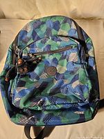 Full front view of Kipling knapsack with geometric pattern and visible monkey keychain