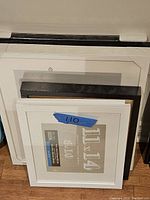 Five picture frames stacked, showing variety in size and color of borders, dimensions labeled on inner protective paper.