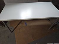 Image showing the white rectangular table with metal legs in a basement setting.