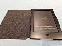 Kobo e-reader displaying low battery warning inside its protective case, case open showing fabric interior cover.