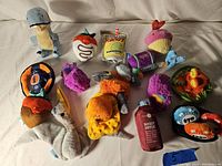 Lot of 14 assorted Bark Box dog toys, soft plush in various whimsical shapes and colors including dinosaur, tomato, cupcake, bird, and treat bag.