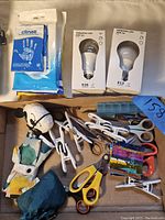 Overview of the lot showing disinfecting wipes, two IKEA TRADFRI LED bulbs in boxes, various scissors, clips, a small figurine, and a multicolored item.