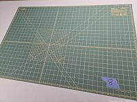 Top-down image of the green OLFA rotary cutting mat showing its full surface with measurement grid and angle guides.