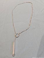 A sterling silver necklace laid out showing its bar and ring toggle clasp pendant