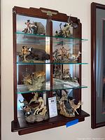 Full view of the wooden display shelf holding nine detailed Franklin Mint American Indian figurines depicting Native American warriors and wildlife scenes.