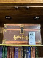 Side view of the closed Harry Potter themed wooden trunk with gold lettering and antique brass effect clasps.