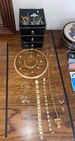 Overview of black lacquer jewelry box on top and assorted jewelry arranged on wooden surface