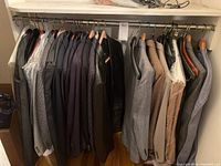 Closet view showing 16 men's jackets and suits hanging, various colors and styles.