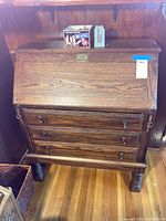 Front view of wooden drop front secretary desk with closed writing surface and two drawers below