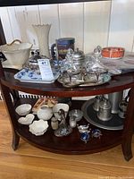 Wide view of salt cellars, pewter, porcelain platters and other ceramic and metal items on a wooden table